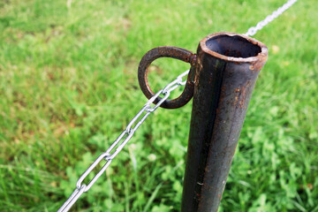A steel chain leads through an iron loop on a pole in the park