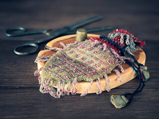Old handcraft supplies for making vintage beaded hand bag with drawstring ties. Concept of hand...