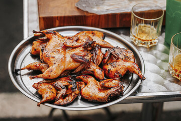 Appetizing crispy grilled quail, glasses of beer, friendly barbecuing outdoors. Summer picnic, backyard barbecue
