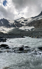 Mountain river. Swiss Alps with snowy peaks. Glacier. Dark and rocky landscape in Switzerland.