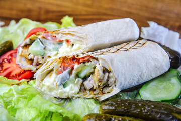 Shawarma sandwich falafel - fresh roll of thin lavash (pita bread) filled with grilled meat, mushrooms, cheese, cabbage, carrots, sauce, green. Traditional Eastern snack.