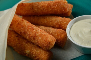 Breaded mozzarella cheese sticks with sauce closeup