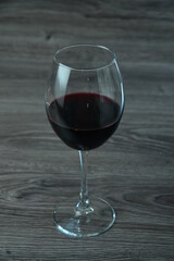 Goblet of red wine on wooden table on wooden background
