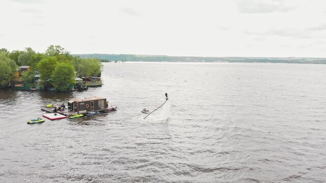 A man training flying over the water on the flyboard near an island - aerial view