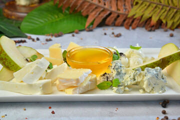 Cheese plate served with pear and honey, mint. Assorted cheeses Camembert, Brie,...
