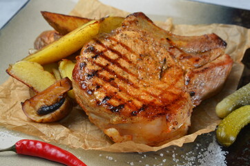 Meat steak with grilled potatoes and vegetables on square plate closeup