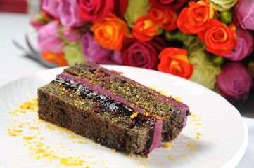 Delicious chocolate cake with chocolate sauce closeup with flowers background
