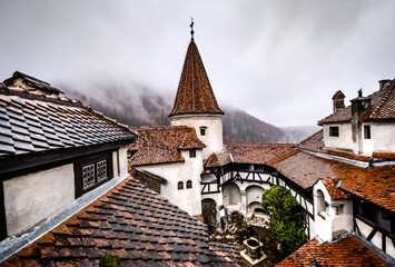 Obraz premium Bran Castle roofs on misty mountains background