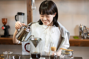 おしゃれな空間で、コーヒーを淹れる若い女性