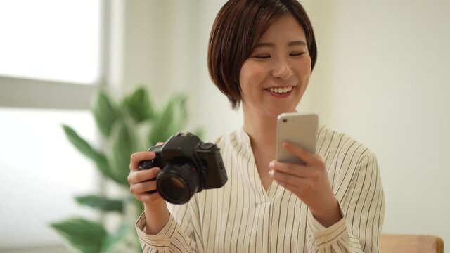 	一眼レフカメラとスマートフォンで撮影した画像を見る女性