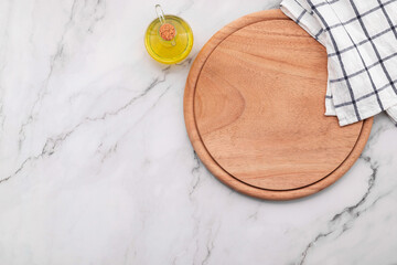 Empty wooden pizza platter with napkin  set up on marble stone kitchen table. Pizza board and tablecloth on white marble background.