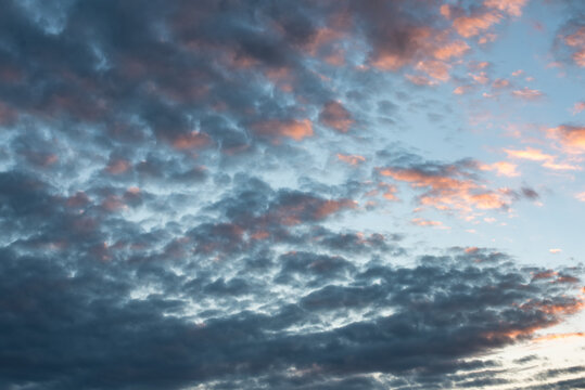 fotografia del cielo tormentoso y tranquilo con nubes cumulus estractus azules, blancas, naranjas y negra , con un molino de agua de fondo, horizontal apaisado.
