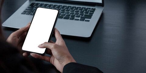Mockup image blank white screen cell phone.women hand holding texting using mobile on desk at home office.