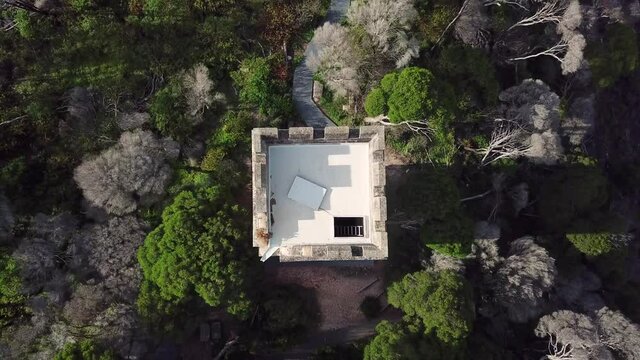 Aerial top down rising higher over an old stone whaling tower standing tall next to the ocean, at Eden Australia