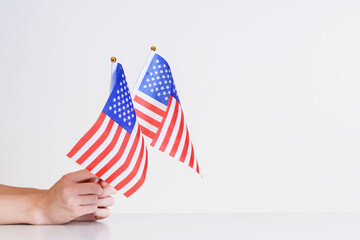 American flags in hands on a light background over the table.Stars and stripes flag setting.Presidential elections.Independence day America.American Flag day.National values.Mini american Flag