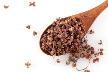 A spoonful of peppercorns on a white background