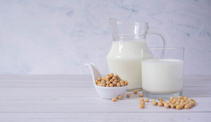 Close up tasty organic homemade soy milk in glass and soybean or soya beans in glass bowl on a wooden table background.Soy milk is a beverage made from soy.Alternative milk and healthy concept.