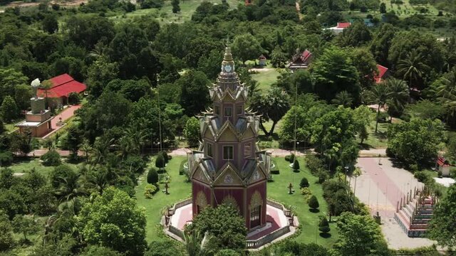 Beautiful octagonal buddhist shrine with birds flying around. Drone orbit rotate full 360 degrees in the lush green foot hills of Phnom Kulen national park, Cambodia.