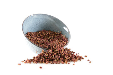 Full bowl of peppercorns sprinkled on white background
