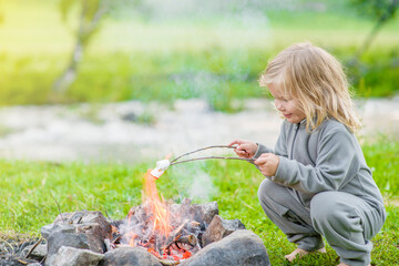 Little girl roasts marshmallows on campfire