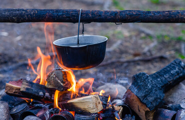 Preparing food on campfire in an open fire in a travel pot in wild camping