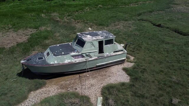 Abandoned old fishing boat carcass shipwreck in shipyard low tide mud flats graveyard orbit right