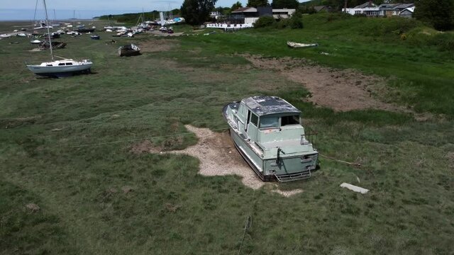 Abandoned old fishing boat carcass shipwreck in shipyard low tide mud flats graveyard right orbit tilt up