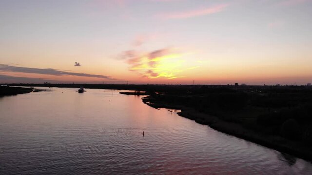 Colorful Sunset Sky With Silhouetted Barge Ship Sailing Across The River. - Wide Shot