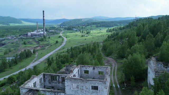 an old building of a thermal power station against the background of destroyed buildings of an abandoned factory or mine in a picturesque place in nature. Tuim, Tuimsky failure, Russia. travel and