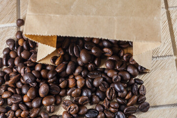 Coffee beans in a brown paper bag on wooden background.