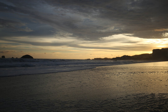landscape with sea sunset on beach, clouds, sun and island.
Beautiful sunrise over the sea, people walking