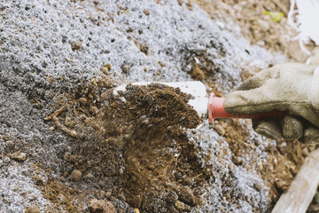 Gloved hand preparing compost with a mixture of substrate of animal origin and vegetable ash to sow garden and garden plants