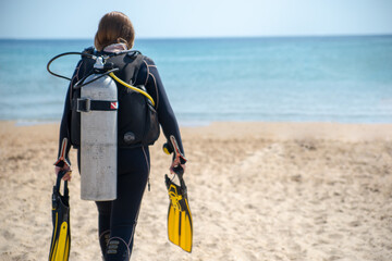 Scuba Diver. Diver girl walks along the beach towards the sea