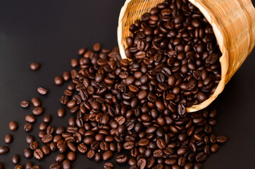 basket of coffee beans poured on the wooden plank and Black background