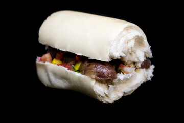 Choripán with Creole sauce, typical hot dog from Argentina. Black background