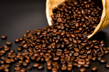 basket of coffee beans poured on the wooden plank and Black background