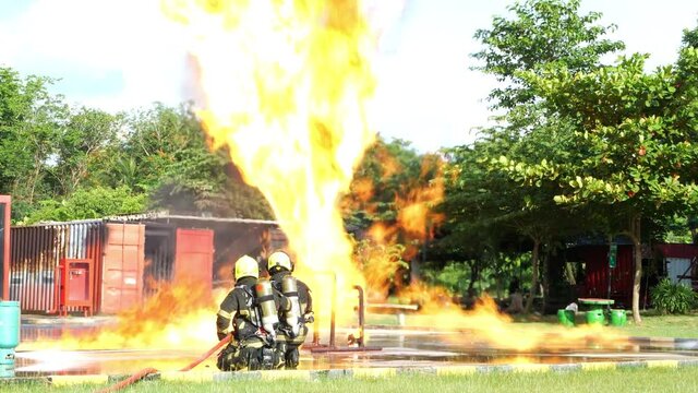 Two firefighter water spray by high pressure nozzle in fire fighting operation. Fire and rescue training school regularly to get ready. Gas leaking from an industrial pressure gauge.