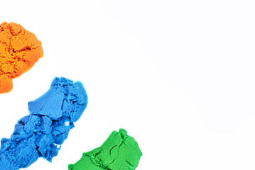 Different colors of bright kinetic sand on a white background.
