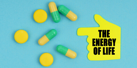 On a blue background, there are pills and a hand-sticker with the inscription - The energy of life
