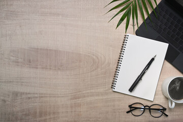 Eye glasses, coffee cup and notebook on wooden background.