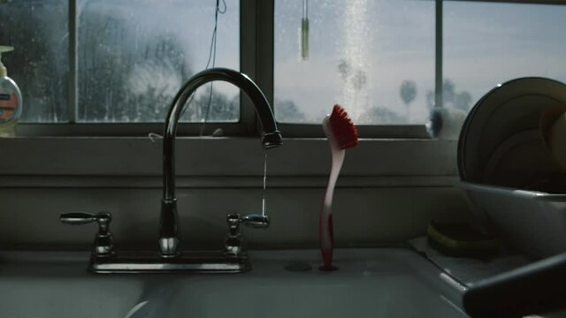 Beautiful cinematic shot of a person turning off a dripping kitchen sink tap