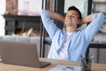 Happy worker man resting in a chair at workplace in office, after a long day at work