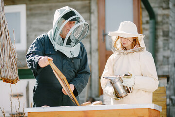Man and woman beekepers inspecting beehive outdoors