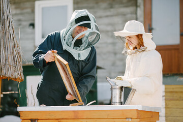Man and woman beekepers inspecting beehive outdoors