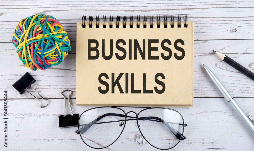 Poster notebook with text business skills and office supplies. view from above. closeup on white background