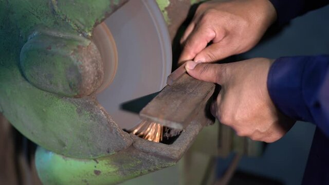 A man grinding a tool bit by using a grinding machine