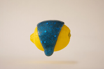 A drop of blue slime runs down the yellow lemon. Bright color contemporary fun sticky mucus.