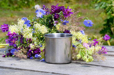 Hiking steel mug stands on a gray wooden table near the flowers