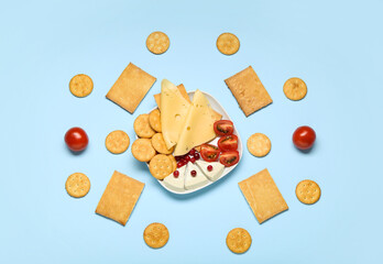 Plate with tasty crackers and snacks on color background