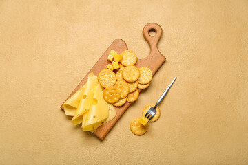Board with tasty crackers and cheese on color background